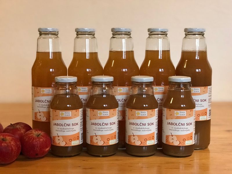 Image showing labeled bottles of apple juice with apples in the background.